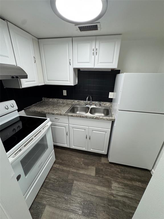 A kitchen features white cabinets, a granite countertop, a stainless steel sink, and white appliances — 1745-1745 NE 2ND STREET UNIT 3, OCALA, FL