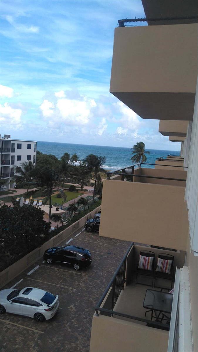 An elevated view from a balcony overlooking a parking lot, palm trees, and the ocean — 2000 S Ocean Boulevard # 4a, Pompano Beach FL 33062, POMPANO BEACH, FL