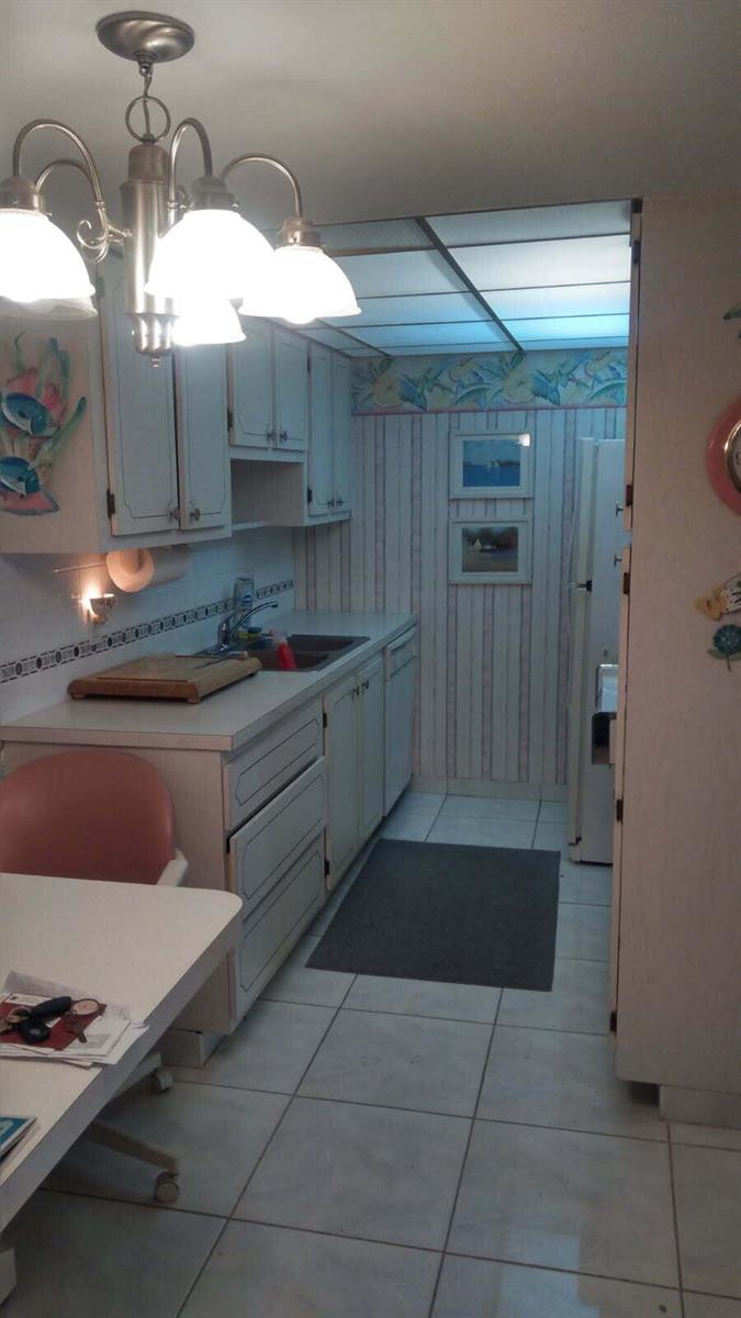 A kitchen features white cabinets, striped wallpaper, a drop ceiling, and a chandelier — 2000 S Ocean Boulevard # 4a, Pompano Beach FL 33062, POMPANO BEACH, FL