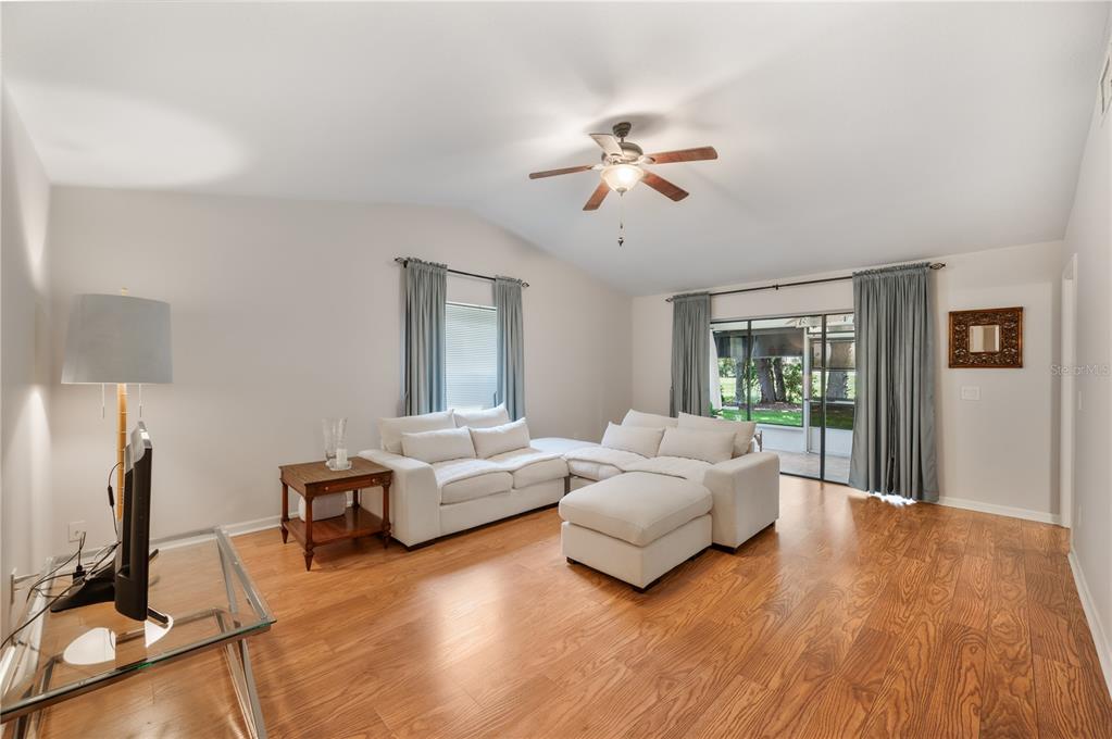 A living room with hardwood floors, a white sectional sofa, and sliding glass patio doors — 26 BUCK CIRCLE, HAINES CITY, FL