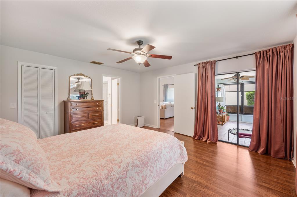 A bedroom with wood flooring, a ceiling fan, a dresser, and sliding glass doors — 26 BUCK CIRCLE, HAINES CITY, FL