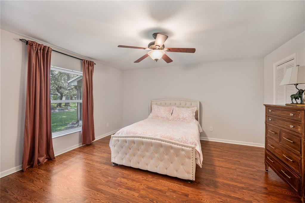 A bedroom features a tufted bed, wooden dresser, ceiling fan, and window with brown curtains — 26 BUCK CIRCLE, HAINES CITY, FL