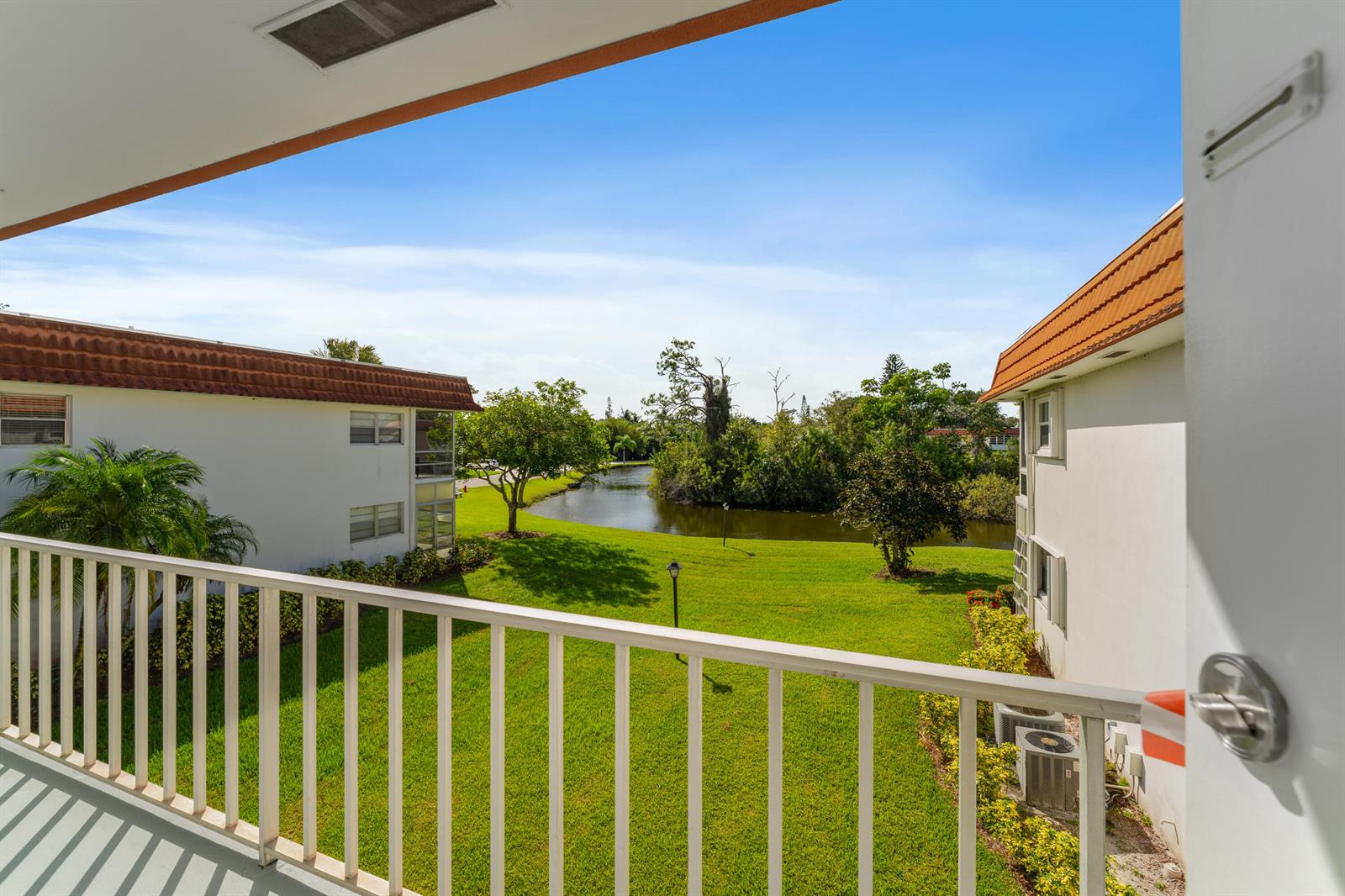A view from a balcony overlooking a grassy lawn, a small pond, and apartment buildings — 1225 NW 21st Street # 710, Stuart FL 34994, STUART, FL