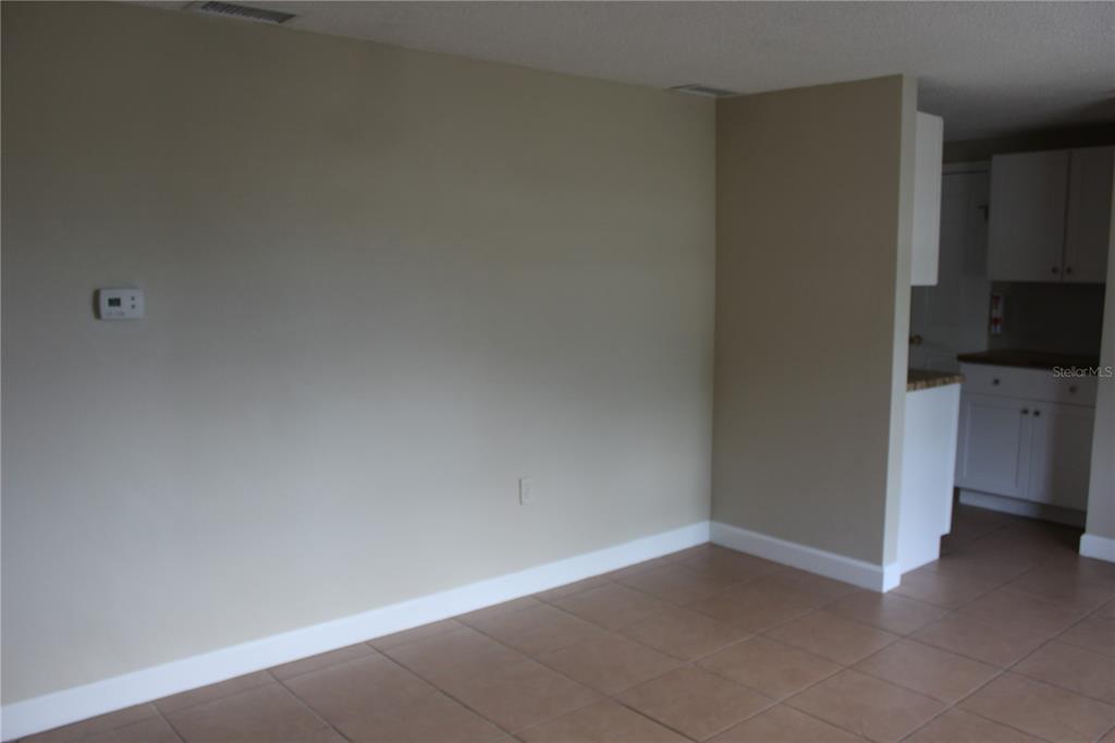 An empty room with beige walls, white baseboards, and light brown tile flooring — 4424 TERRY LOOP, NEW PORT RICHEY, FL