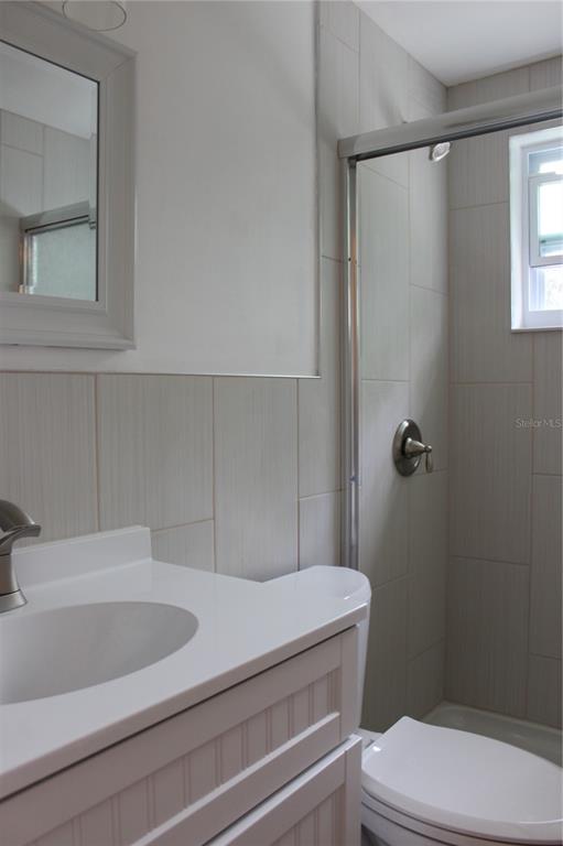 A bathroom features a white vanity, a tiled shower stall, and a toilet — 4424 TERRY LOOP, NEW PORT RICHEY, FL