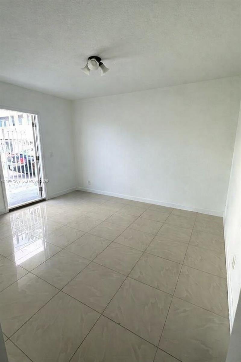 An empty room with white walls, light-colored tile flooring, and a glass door — 1770 NW 19th Ter # G, Miami FL 33125, MIAMI, FL