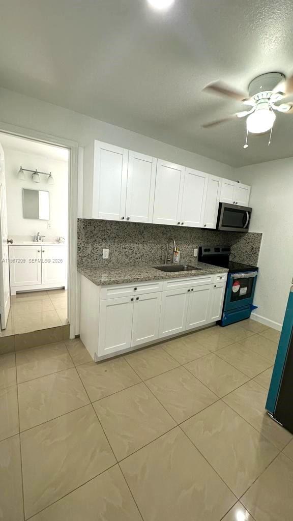 A kitchen features white cabinets, granite countertops, and a view into an adjacent bathroom — 1770 NW 19th Ter # G, Miami FL 33125, MIAMI, FL
