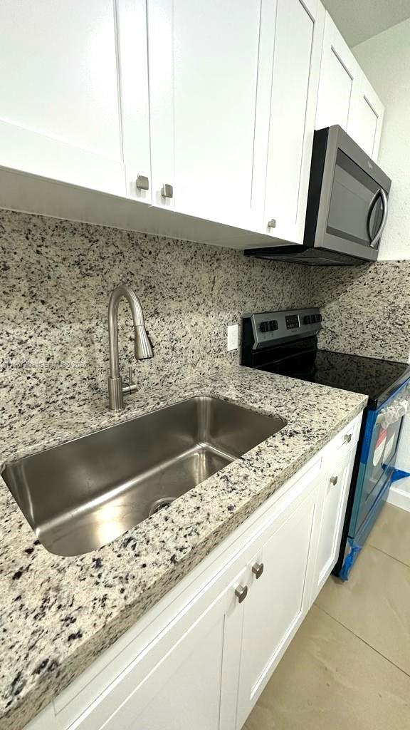 A kitchen features white cabinets, granite countertops, a stainless steel sink, and black appliances — 1770 NW 19th Ter # G, Miami FL 33125, MIAMI, FL