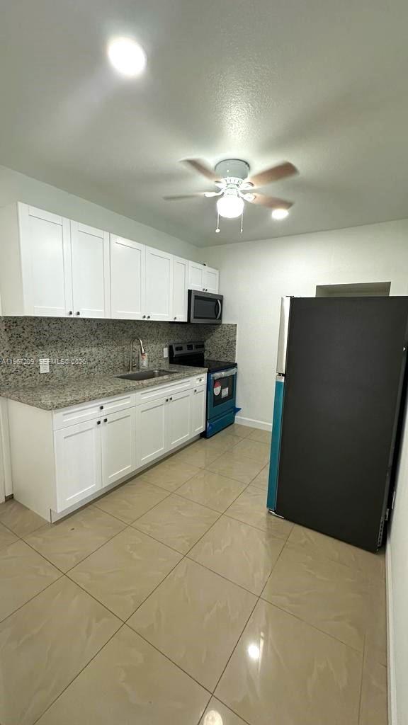 A kitchen features white cabinets, granite countertops, stainless steel appliances, and light tile flooring — 1770 NW 19th Ter # G, Miami FL 33125, MIAMI, FL