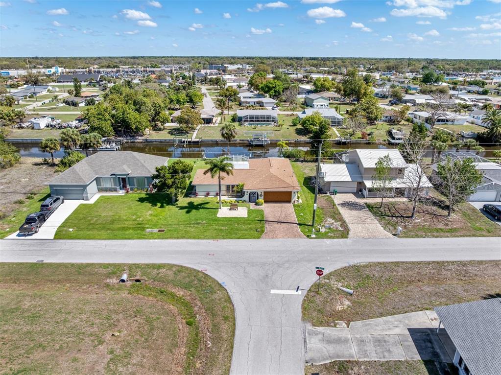 An aerial view shows three houses along a canal with a street in the foreground — 2220 BROAD RANCH DRIVE, PORT CHARLOTTE, FL