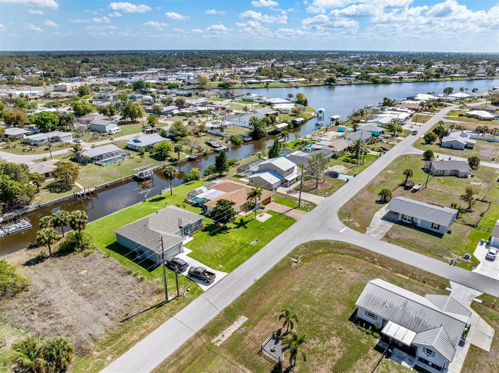 An aerial view shows houses along a canal in a suburban neighborhood under a blue sky — 2220 BROAD RANCH DRIVE, PORT CHARLOTTE, FL