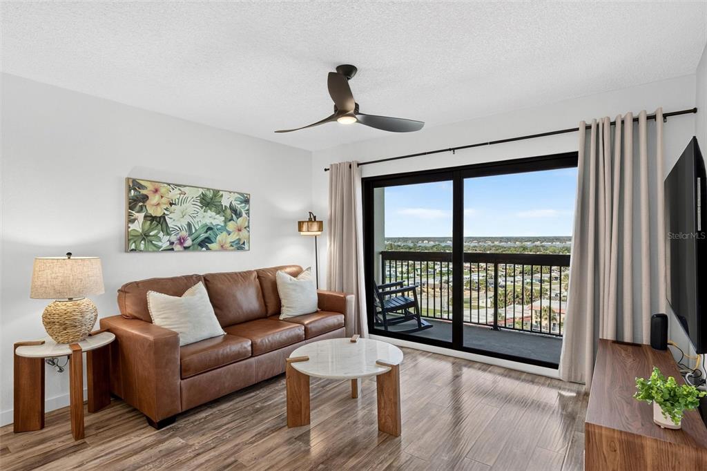 A living room features a brown leather sofa, marble coffee table, and balcony with water views — 1513 OCEAN SHORE BOULEVARD UNIT 10A, ORMOND BEACH, FL