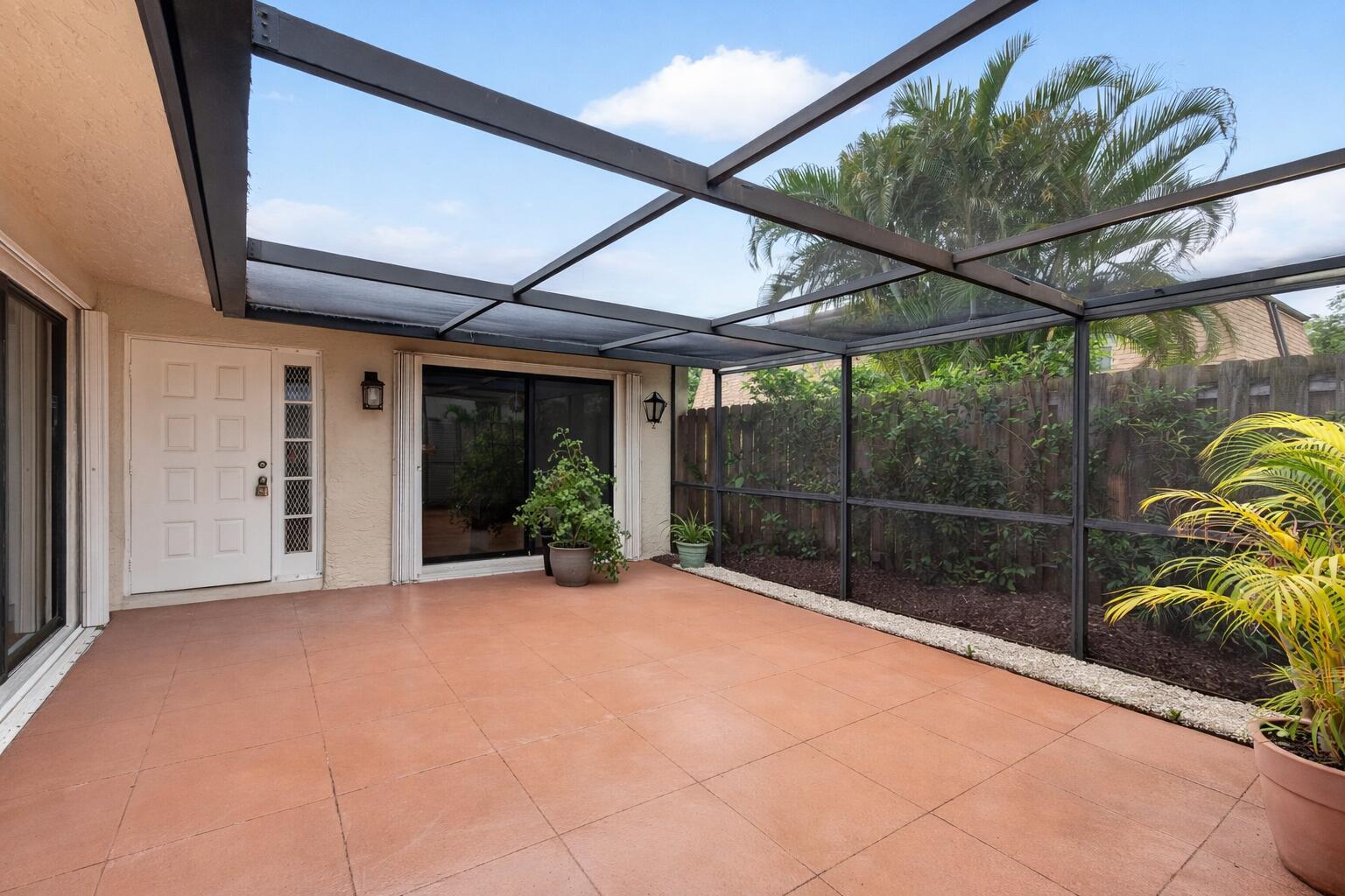 A screened-in patio features terracotta tile flooring, a white door, and a sliding glass door — 801 NW 30th Avenue # C, Delray Beach FL 33445, DELRAY BEACH, FL