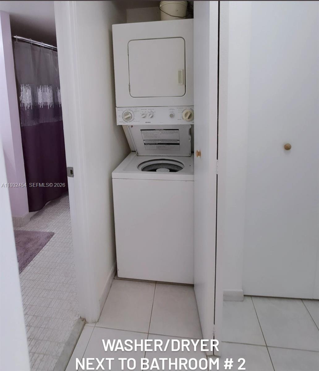 A stacked washer and dryer unit is located in a small closet next to a bathroom — SUNNY ISLES BEACH, FL