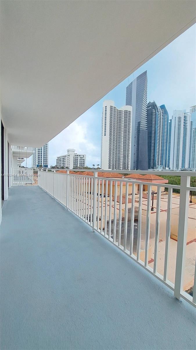 A balcony with a white metal railing overlooks a city skyline with tall buildings — SUNNY ISLES BEACH, FL