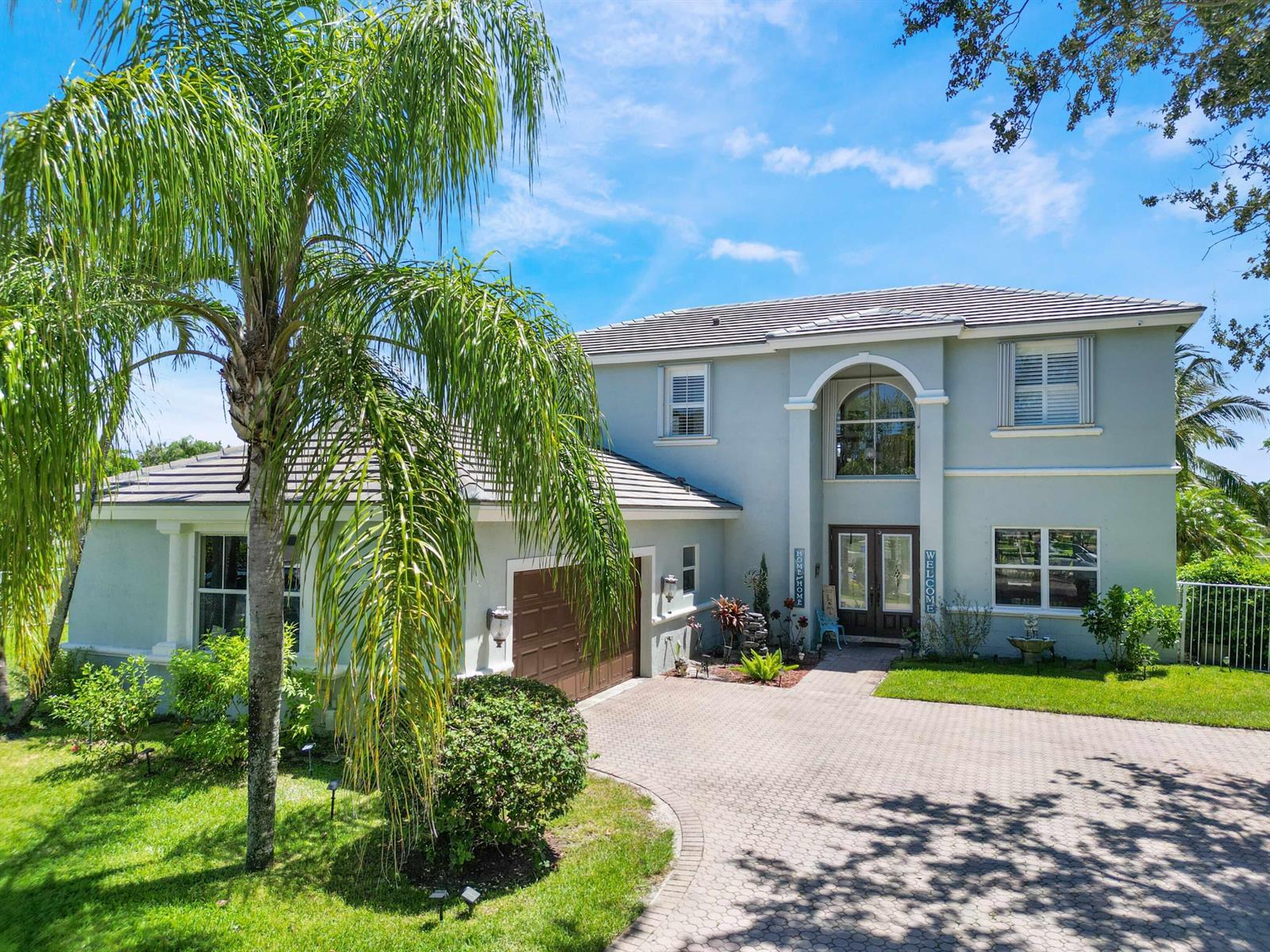 A two-story light blue house with a brown garage and a paved driveway — 6025 Indian Forest Circle, Lake Worth FL 33463, LAKE WORTH, FL