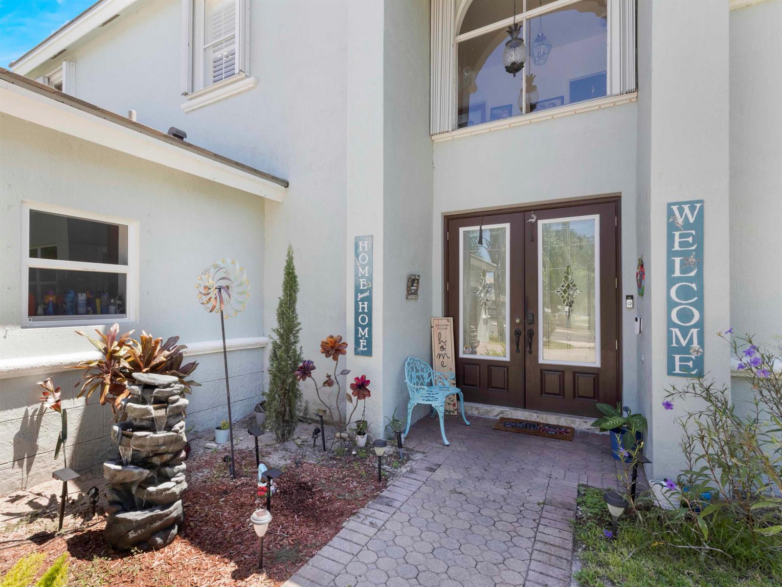 The exterior of a two-story home features a double front door, fountain, and walkway — 6025 Indian Forest Circle, Lake Worth FL 33463, LAKE WORTH, FL