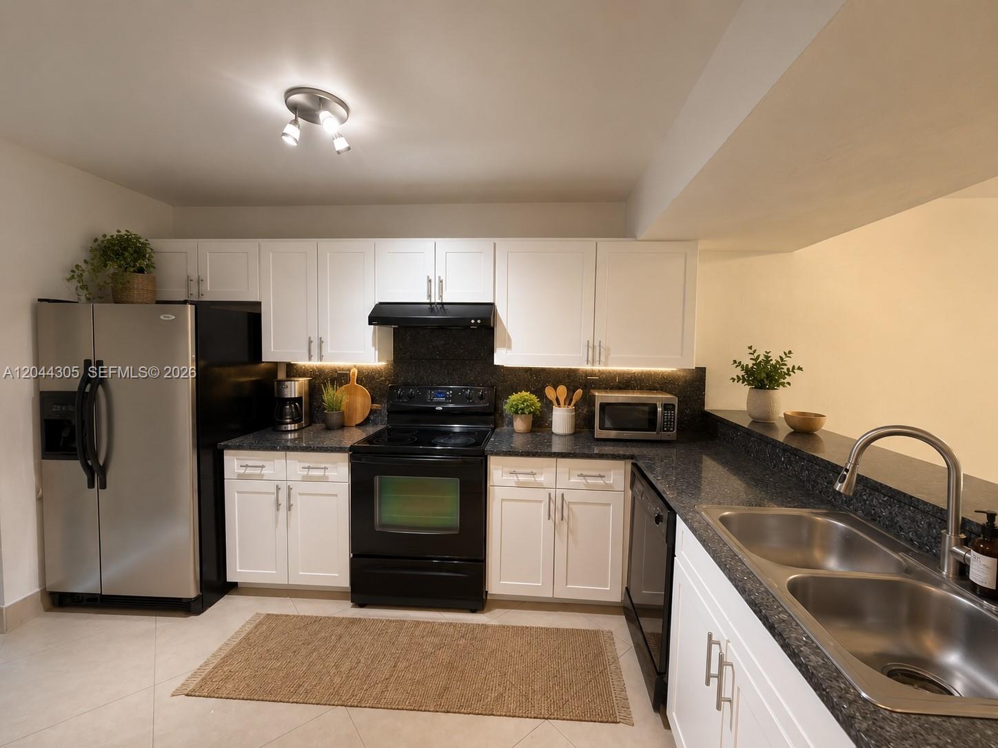 A kitchen features white cabinets, black appliances, dark countertops, and a stainless steel refrigerator — 862 Crystal Lake Dr, Deerfield Beach FL 33064, DEERFIELD BEACH, FL