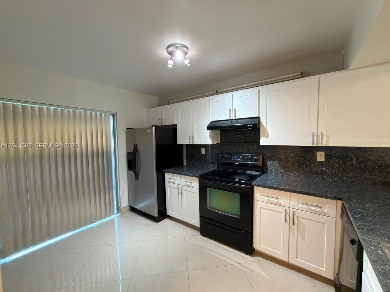 A kitchen features white cabinets, dark granite countertops, black appliances, and light-colored tile flooring — 862 Crystal Lake Dr, Deerfield Beach FL 33064, DEERFIELD BEACH, FL