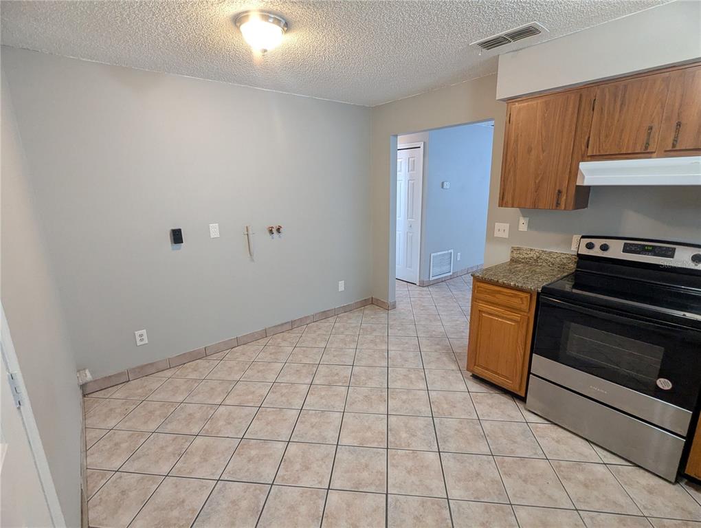 A kitchen features tile flooring, wood cabinets, a stainless steel stove, and laundry hookups — 910 SOUTH CENTER STREET UNIT 910, EUSTIS, FL