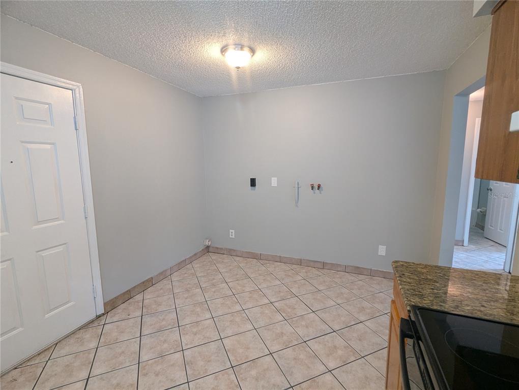 A laundry area with tile flooring, gray walls, and plumbing hookups for a washer and dryer — 910 SOUTH CENTER STREET UNIT 910, EUSTIS, FL