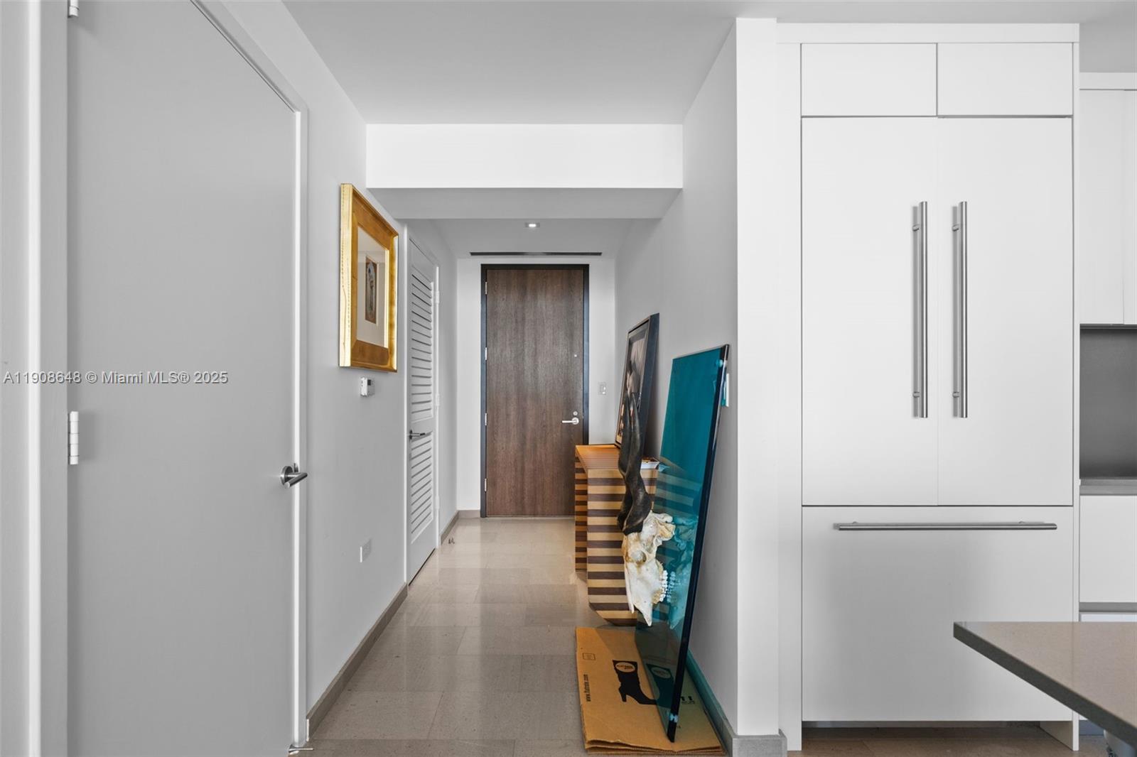 A hallway with light tile flooring leads to a dark wood door — 68 SE 6th St # 2505, Miami FL 33131, MIAMI, FL