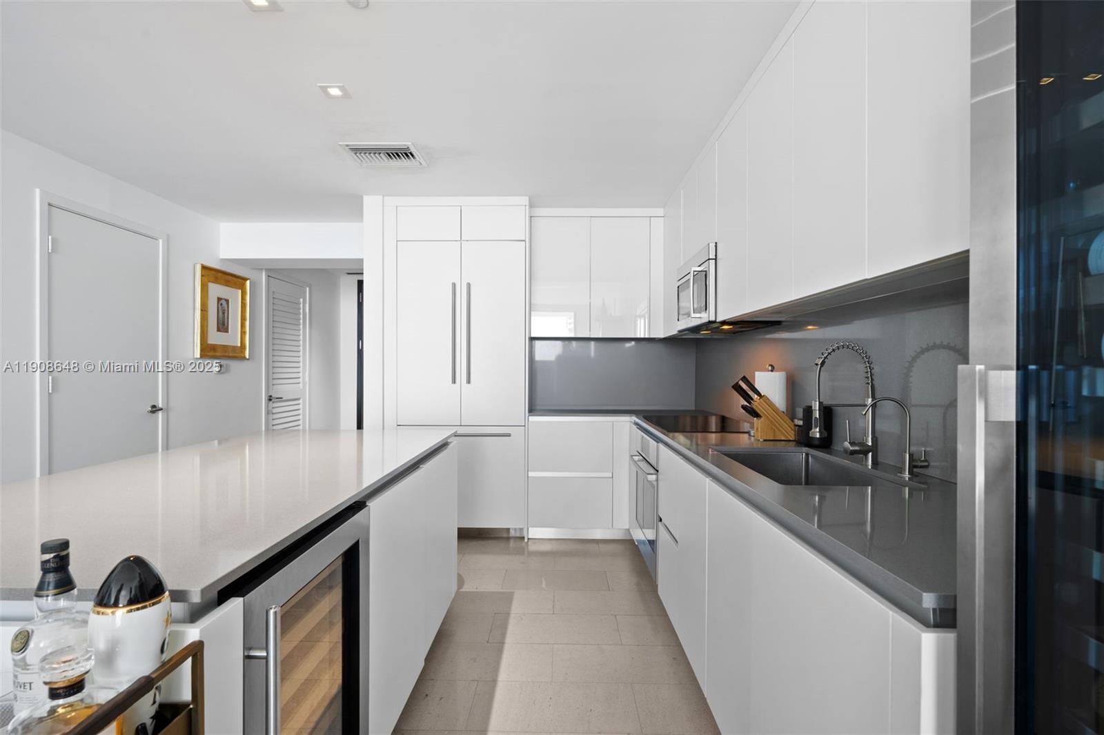 A modern kitchen features white cabinetry, gray countertops, a central island, and stainless steel appliances — 68 SE 6th St # 2505, Miami FL 33131, MIAMI, FL