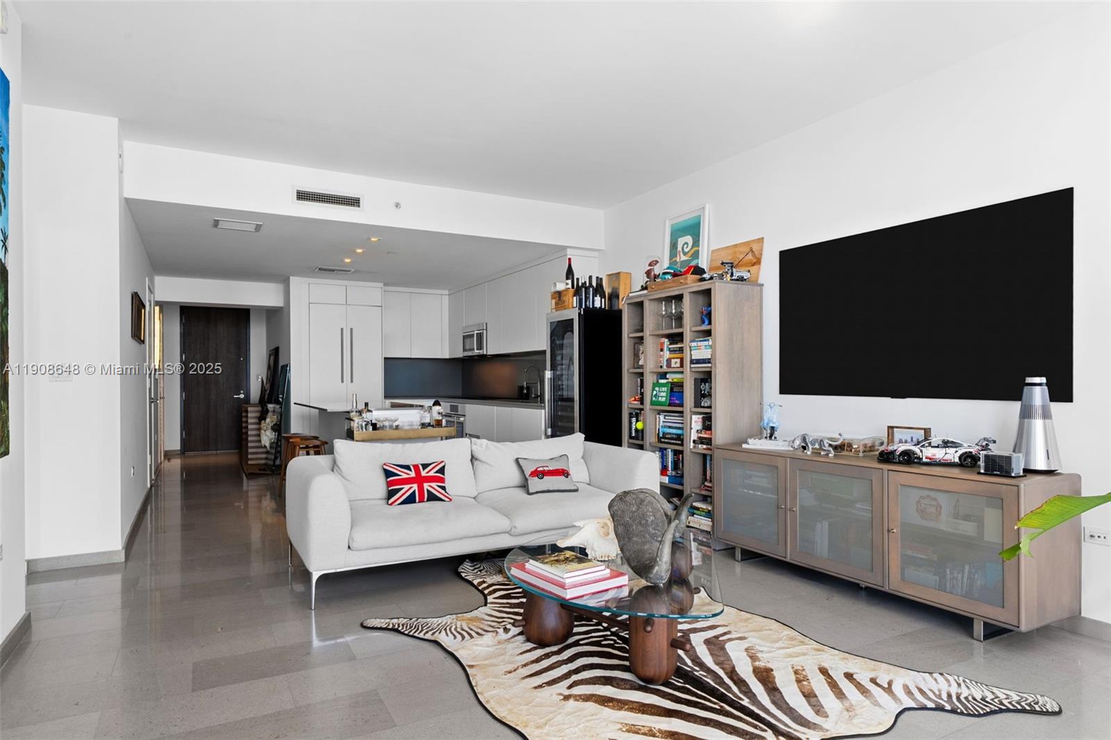A modern living room features a white sofa, zebra-print rug, and a large wall-mounted television — 68 SE 6th St # 2505, Miami FL 33131, MIAMI, FL