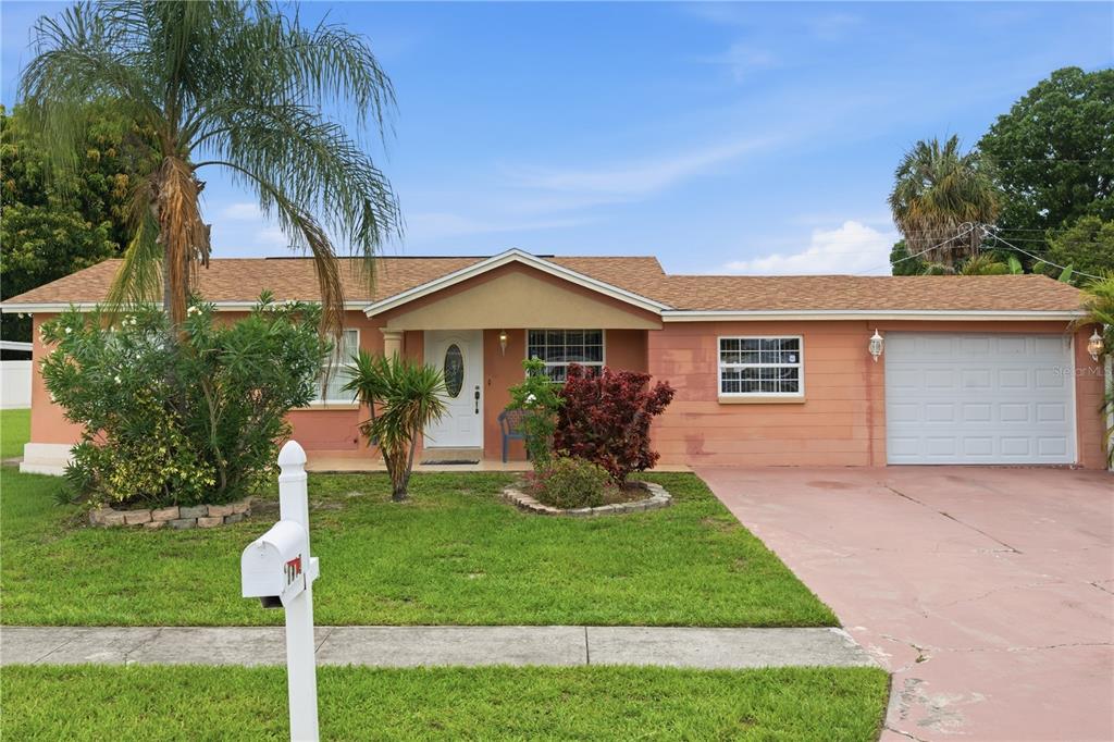 A single-story peach-colored house with a shingled roof, a front lawn, and a garage — 4914 HOLIDAY DRIVE, TAMPA, FL
