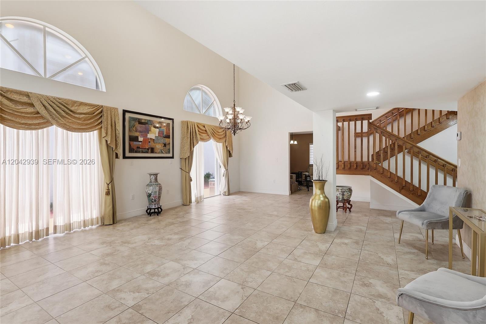 A spacious living area features tile flooring, a vaulted ceiling, arched windows, and a staircase — 15652 SW 91st Ln, Miami FL 33196, MIAMI, FL