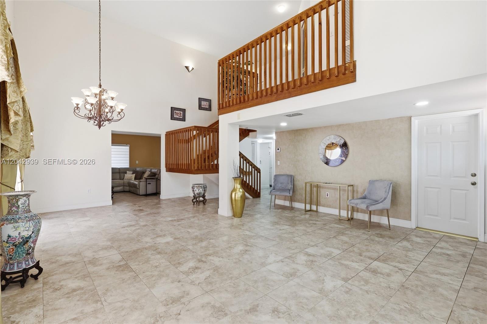 A spacious foyer features tile flooring, a wooden staircase, a chandelier, and a loft balcony — 15652 SW 91st Ln, Miami FL 33196, MIAMI, FL