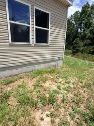 The exterior side of a house with beige vinyl siding and a concrete block foundation — 1835 SPRINGHEAD DRIVE, DELTONA, FL