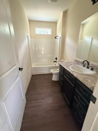 A bathroom features a white tub-shower combo, a dark vanity with a sink, and flooring — 1835 SPRINGHEAD DRIVE, DELTONA, FL