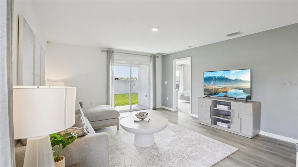 A living room features a gray sofa, a white coffee table, and a television console — 15030 COLTMAN HILL PLACE, WIMAUMA, FL