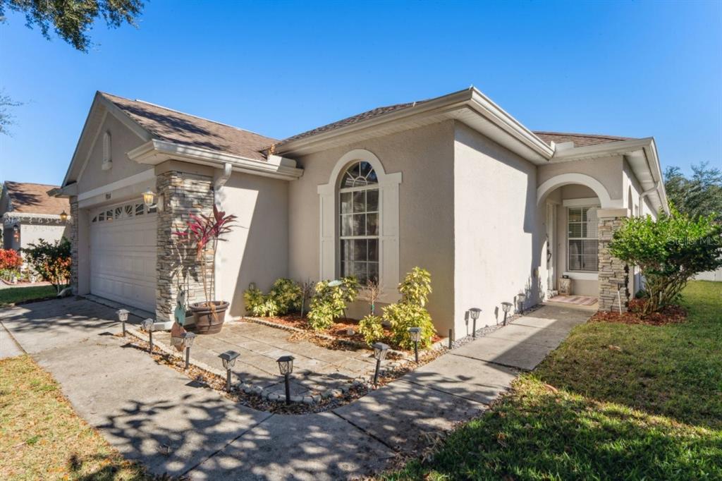 A single-story house with a two-car garage, arched window, and a large tree in front — 9314 CREEDMOOR LANE, NEW PORT RICHEY, FL