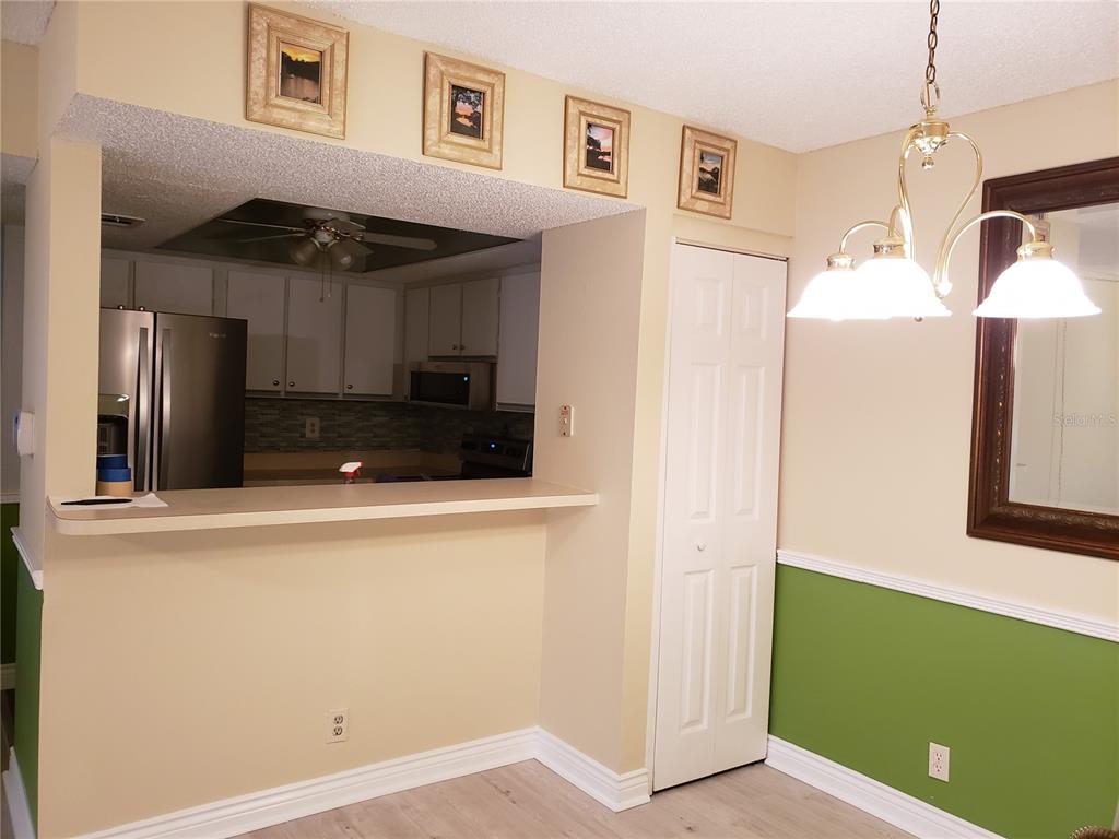 A dining area with a breakfast bar opening into a kitchen with white cabinets — 19505 QUESADA UNIT OO103, PORT CHARLOTTE, FL