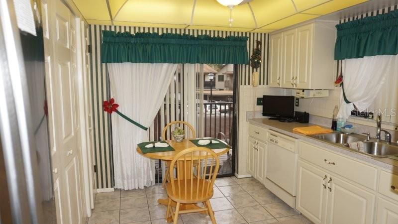 A kitchen with white cabinets, a small wooden dining set, and striped wallpaper — 12917 WEDGEWOOD WAY UNIT C, HUDSON, FL