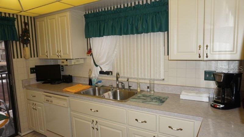 A kitchen features white cabinets, a double-basin sink, a dishwasher, and a coffee maker — 12917 WEDGEWOOD WAY UNIT C, HUDSON, FL