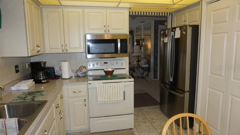 A kitchen features white cabinets, stainless steel appliances, and a tiled backsplash — 12917 WEDGEWOOD WAY UNIT C, HUDSON, FL