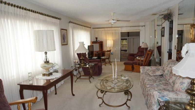A living room features a floral sofa, glass coffee table, and several lamps — 12917 WEDGEWOOD WAY UNIT C, HUDSON, FL