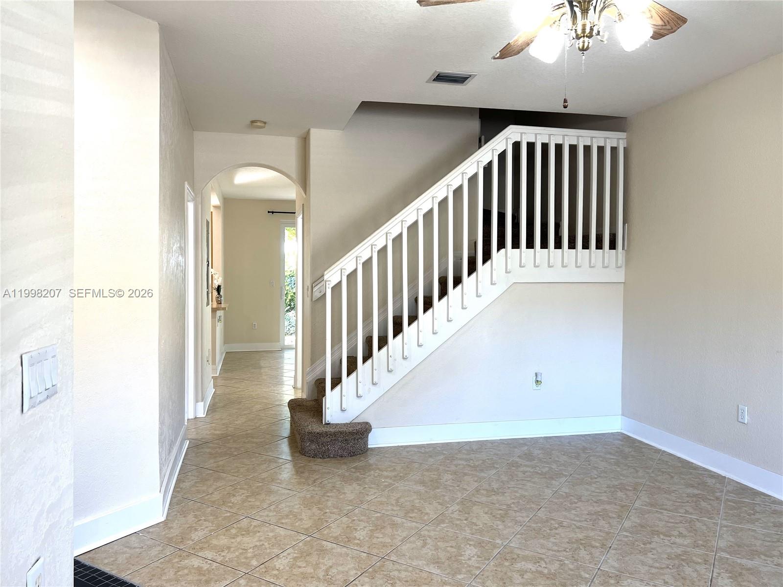 An entryway features tiled flooring, a white staircase with a railing, and a ceiling fan — 3377 Merrick Ln # 707, Margate FL 33063, MARGATE, FL
