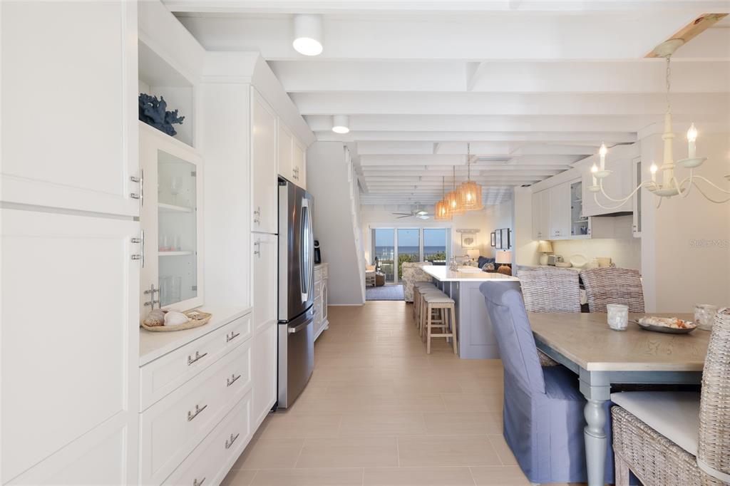 A bright, open-concept kitchen and dining area features white cabinetry, a large island, and ocean views — 420 GULF BOULEVARD UNIT 9, BOCA GRANDE, FL