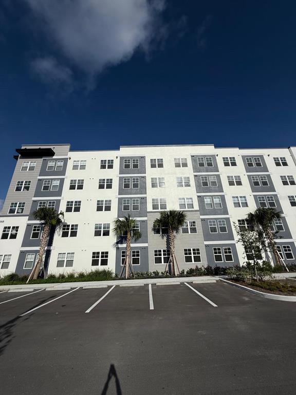 A four-story apartment building with a white and gray facade stands above a parking lot — 5579 PGA BLVD UNIT 524, ORLANDO, FL