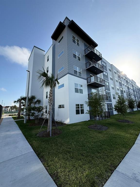 A multi-story apartment building features gray and white siding with several stacked balconies — 5579 PGA BLVD UNIT 524, ORLANDO, FL