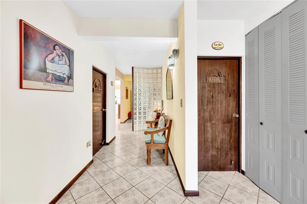 A hallway with tiled floors, a wooden bench, two dark doors, and a glass block wall — 110 FREIRE CALLE RUBI, CIDRA, PR