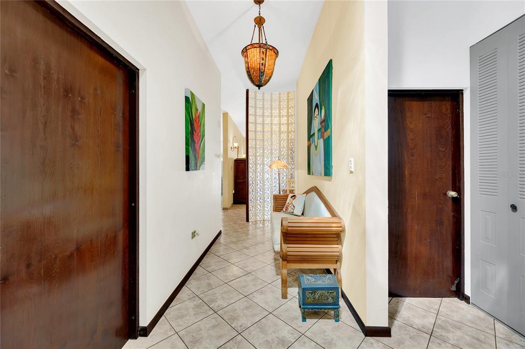 A hallway with tiled floors, a wooden bench, a glass block wall, and a pendant light — 110 FREIRE CALLE RUBI, CIDRA, PR