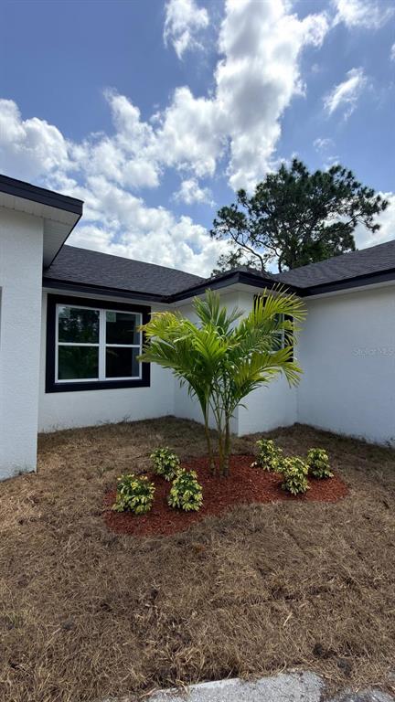 A white house exterior features a palm tree in a mulched bed with pine straw — 2693 JEANNIN DRIVE, NORTH PORT, FL