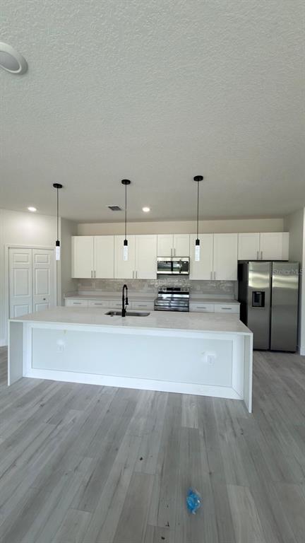 A modern kitchen features white cabinetry, a large central island, and stainless steel appliances — 2693 JEANNIN DRIVE, NORTH PORT, FL