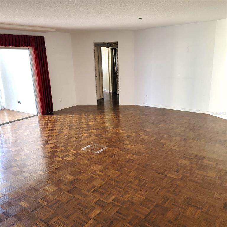 An empty room features parquet wood flooring, white walls, and a sliding glass door — 435 S GULFSTREAM AVENUE UNIT 605, SARASOTA, FL