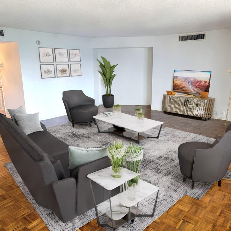 This virtually staged living room features dark gray furniture, a marble coffee table, and parquet flooring — 435 S GULFSTREAM AVENUE UNIT 605, SARASOTA, FL